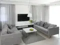 Dwie szare sofy w małym salonie inspiracje. Nowoczesne wnętrze z białym stolikiem i telewizorem.