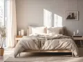 Przytulna sypialnia inspiracje: łóżko z beżową pościelą i narzutą, drewniane meble, jasne zasłony i roślina w doniczce.