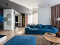 Granatowa sofa z niebieskimi poduszkami, stolik kawowy, dywan i lampa tworzą przytulną przestrzeń.
