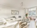 Jasny salon z białymi sofami, szklanym stolikiem i ozdobnym lustrem. Inspiracje salonem w stylu francuskim.
