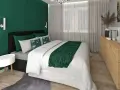 Elegancka sypialnia w butelkowej zieleni i szarości. Ściana za łóżkiem w głębokim odcieniu zieleni, z geometrycznymi panelami. Pościel biała, z zielonym akcentem.