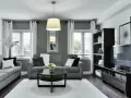 Nowoczesny salon z ciemnymi meblami, szarymi sofami i czarnym stolikiem kawowym. Aranżacje podkreślają elegancję i minimalizm.