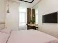 Przytulna, mała sypialnia z oknem, łóżkiem i toaletką.