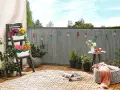 Kolorowe lampki i kwiaty tworzą przytulny balkon tanim kosztem. Drewniana podłoga i wygodne siedzisko zapraszają do relaksu.