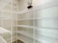 Pusta piwnica z białymi, drucianymi półkami. Idealny pomysł na półki w piwnicy do przechowywania przetworów i narzędzi.