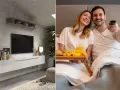 Nowoczesna ściana TV w sypialni z minimalistyczną szafką i parą cieszącą się porankiem w łóżku z tacą śniadaniową.