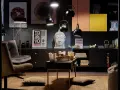 Salon w stylu eklektycznym z motywami azjatyckimi. Wygodne fotele, stolik z poduszkami, rzeźba Buddy i plakaty z Japonii tworzą przytulną atmosferę.