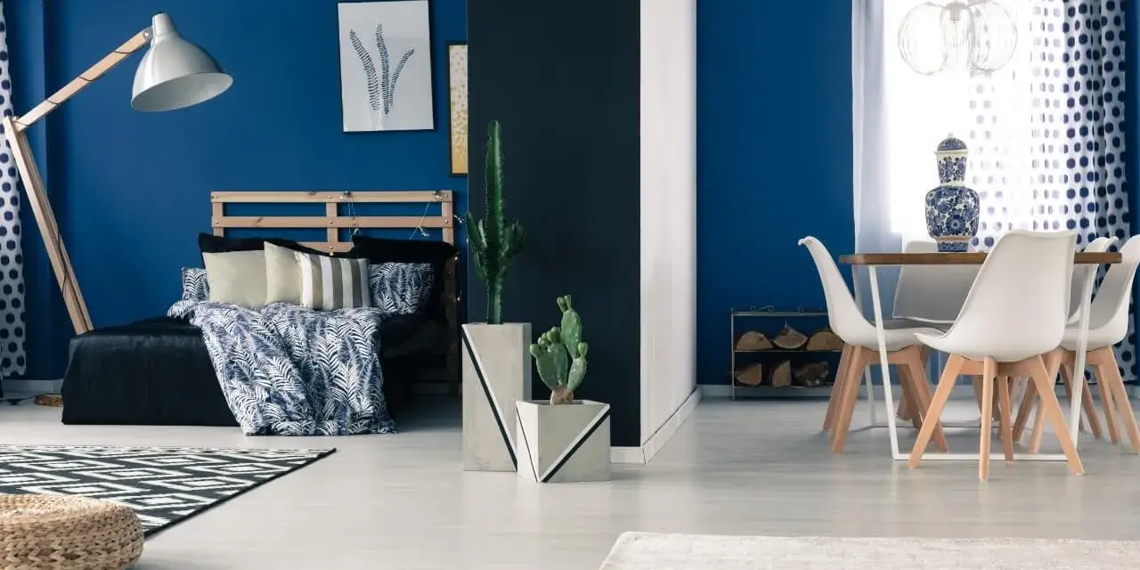 Granatowy salon inspiracje: sypialnia z łóżkiem i stolik z krzesłami.