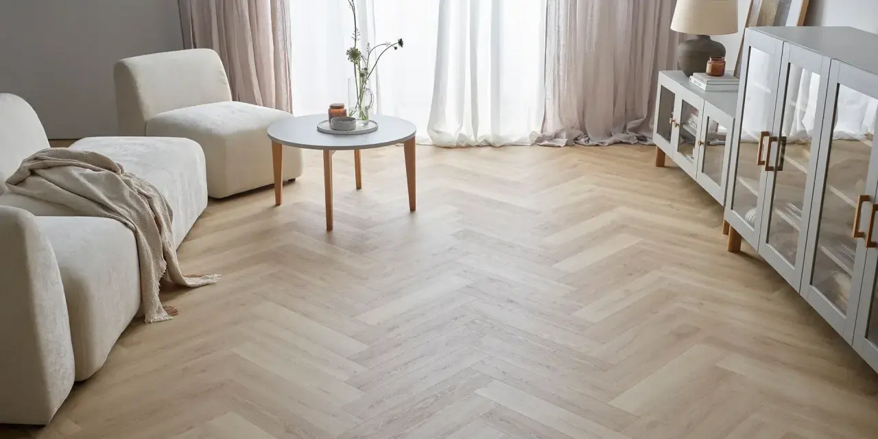 Jasna podłoga w jodełkę w salonie, z beżową kanapą i fotelami, tworzy przytulną atmosferę.