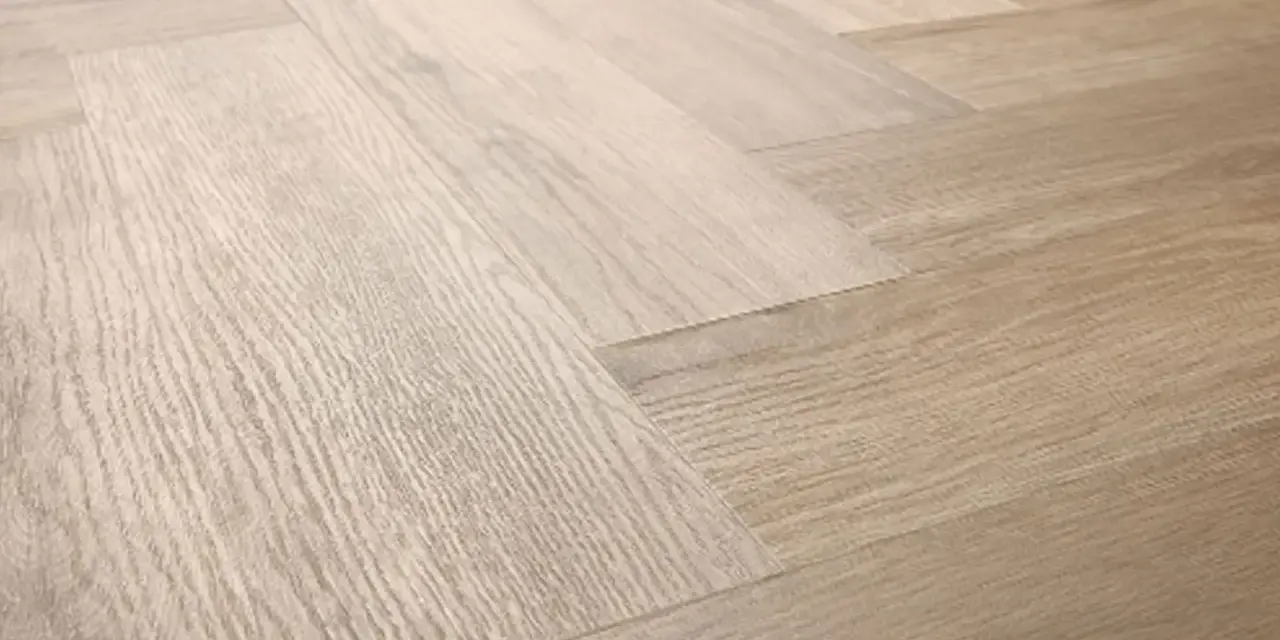 Drewniana podłoga ułożona w jodełkę. Jasne panele tworzą elegancki wzór, który sprawia, że wnętrze wydaje się przestronniejsze.