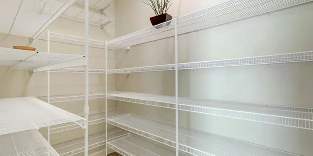 Pusta piwnica z białymi, drucianymi półkami. Idealny pomysł na półki w piwnicy do przechowywania przetworów i narzędzi.