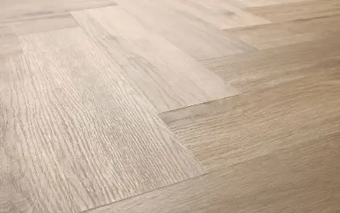 Drewniana podłoga ułożona w jodełkę. Jasne panele tworzą elegancki wzór, który sprawia, że wnętrze wydaje się przestronniejsze.