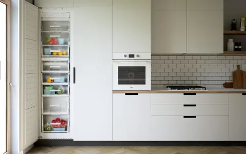 Nowoczesna kuchnia z otwartą lodówką pełną świeżych warzyw i owoców, piekarnikiem i szufladami co pod szafki kuchenne.