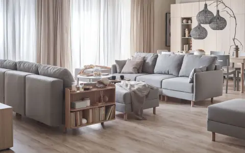 Przytulna aranżacja salonu z szarymi sofami, drewnianymi meblami i jasnymi zasłonami.