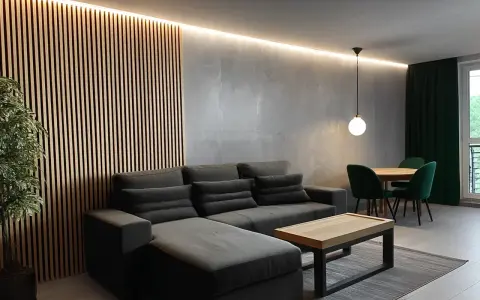 Nowoczesny salon w stylu loft. Aranżacje z szarą sofą, drewnianą ścianką i zielonymi akcentami.