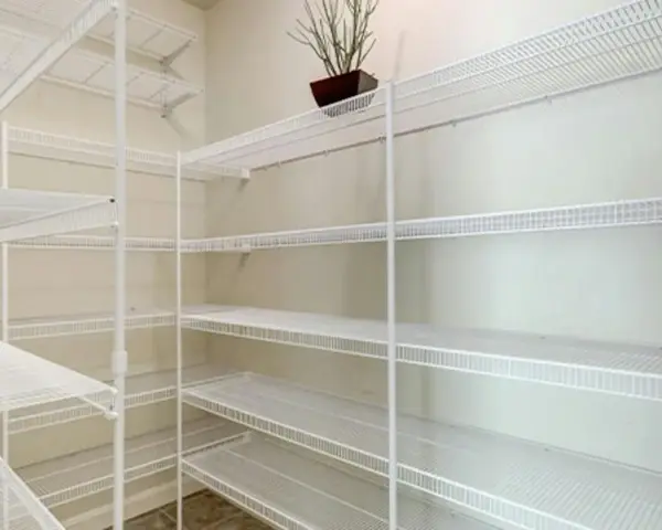 Pusta piwnica z białymi, drucianymi półkami. Idealny pomysł na półki w piwnicy do przechowywania przetworów i narzędzi.