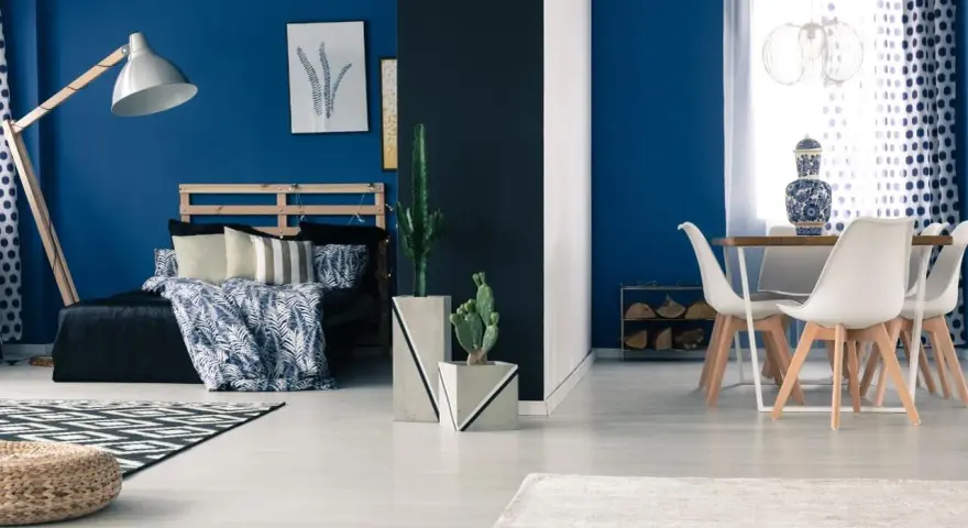 Granatowy salon inspiracje: sypialnia z łóżkiem i stolik z krzesłami.