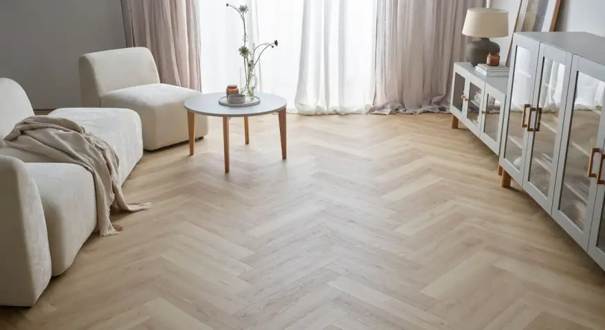 Jasna podłoga w jodełkę w salonie, z beżową kanapą i fotelami, tworzy przytulną atmosferę.