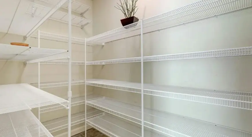 Pusta piwnica z białymi, drucianymi półkami. Idealny pomysł na półki w piwnicy do przechowywania przetworów i narzędzi.