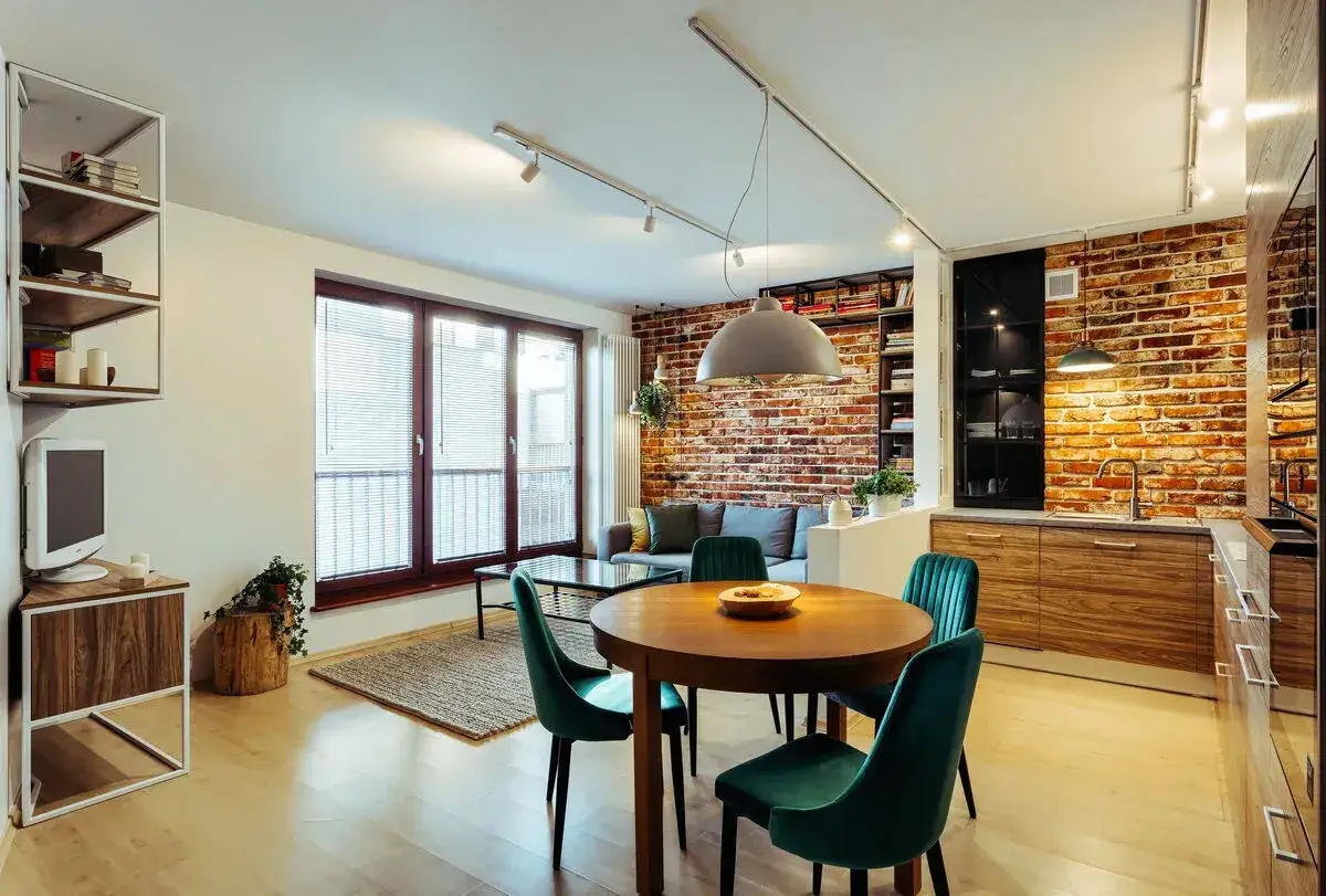 Nowoczesny salon w stylu loft: ceglana ściana, drewniane meble, welurowe krzesła. Aranżacje tworzą przytulną przestrzeń.