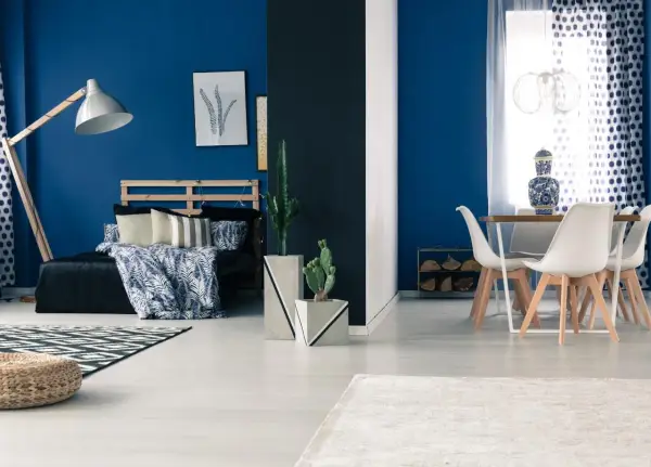 Granatowy salon inspiracje: sypialnia z łóżkiem i stolik z krzesłami.