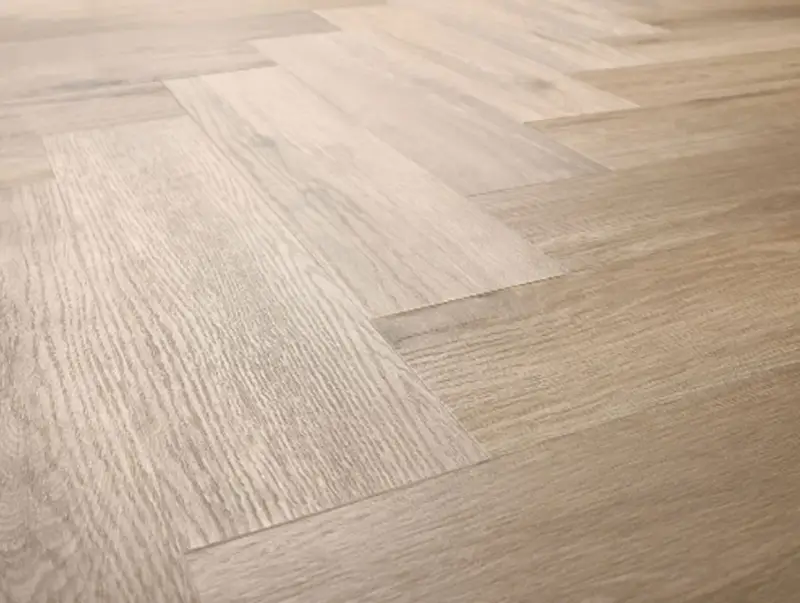 Drewniana podłoga ułożona w jodełkę. Jasne panele tworzą elegancki wzór, który sprawia, że wnętrze wydaje się przestronniejsze.